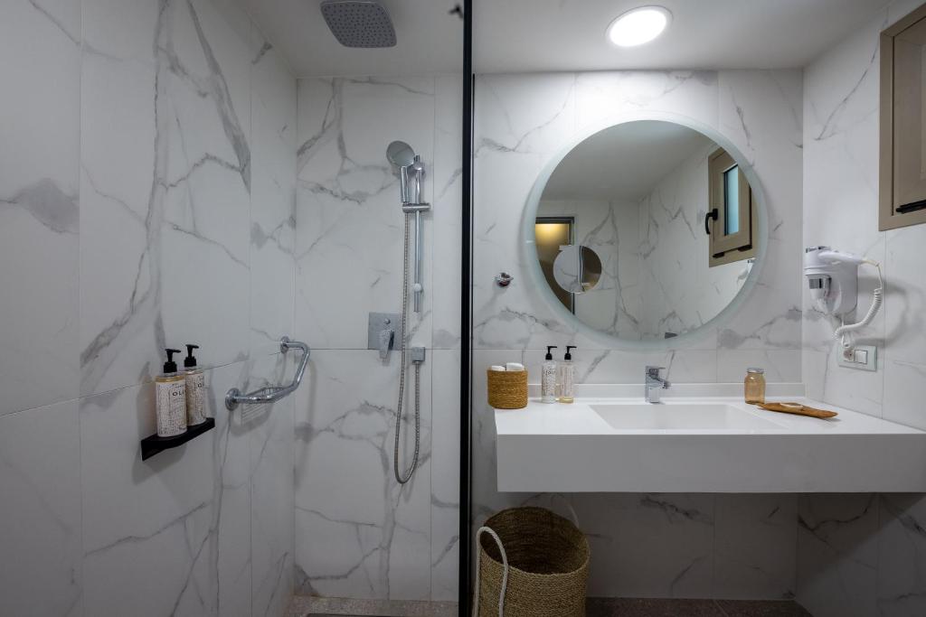 Mūsdienīgs vannas istabas interjers ar marmora izskatu, dušu un apaļu spoguli. Tajā ir higiēnas piederumi un minimālistiska dizaina izskats.