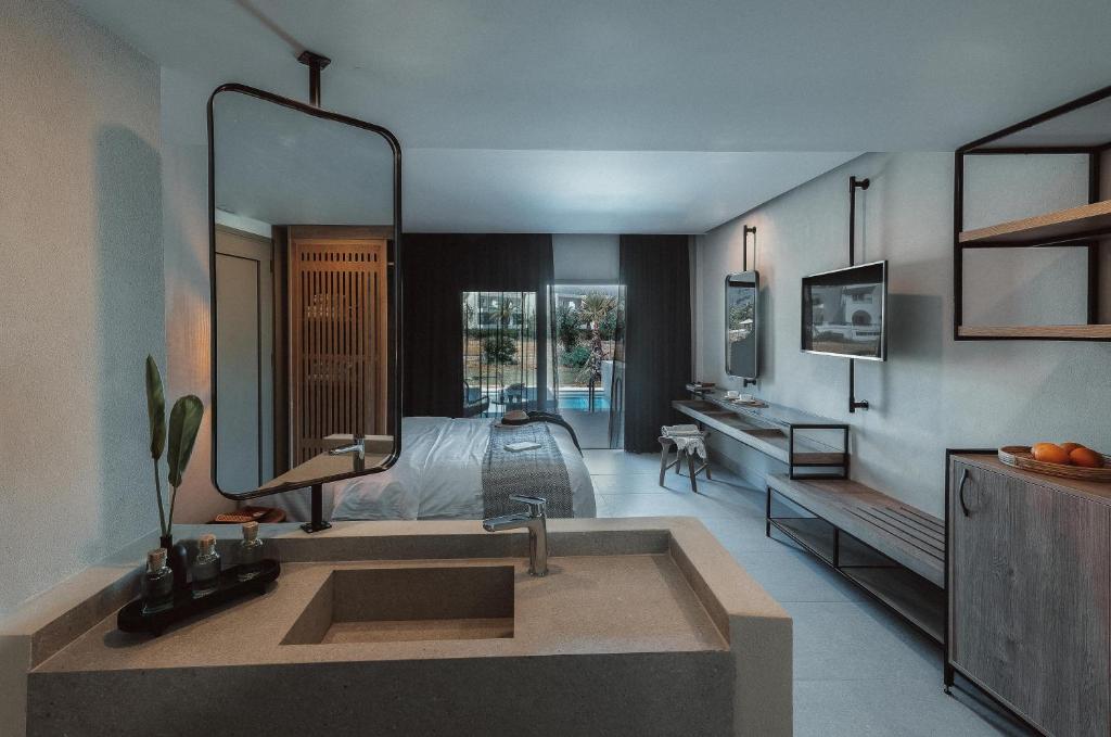 Mūsdienīga viesnīcas istaba ar minimālistisku dizainu, iekļaujot vannas istabu, lielu spoguli un skatu uz baseinu. Interjerā ir izmantoti dabīgi materiāli un neitrālas krāsas.