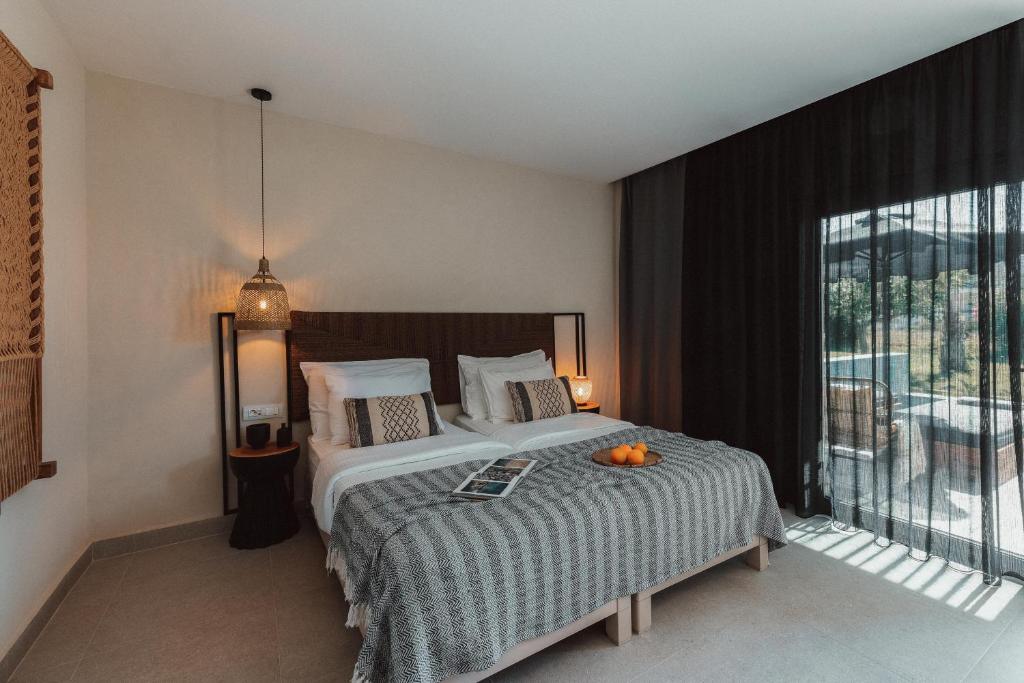 Mūsdienīgs guļamistabas interjers ar ērtu gultu, dekoratīviem spilveniem un jauku apgaismojumu. Logs ar caurspīdīgu aizkaru piešķir telpai gaismas un svaiguma sajūtu.