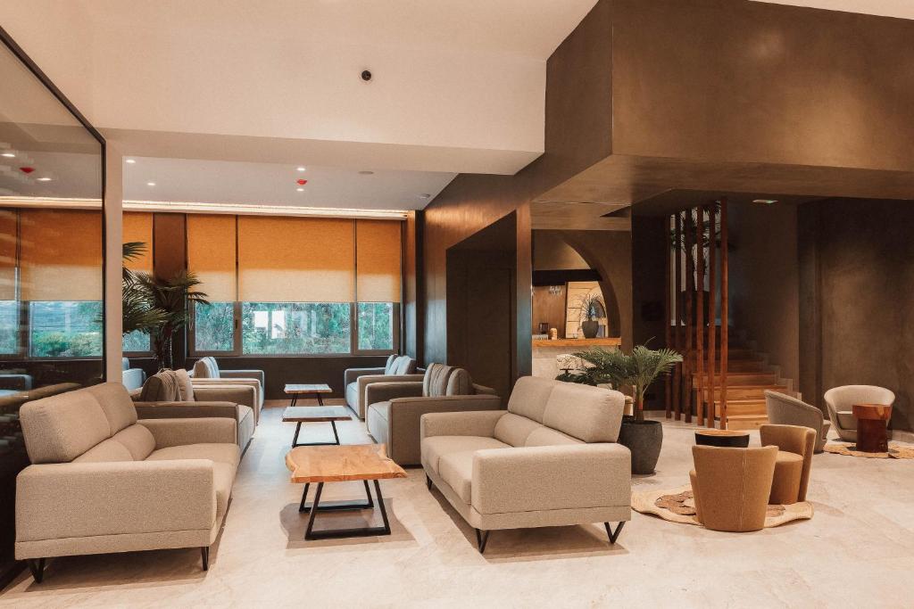 Mūsdienīgs viesnīcas vestibilis ar elegantiem dīvāniem, koka galdiem un dabīgām augu kompozīcijām. Telpa ir gaiša un plaša, radot relaksējošu atmosfēru.