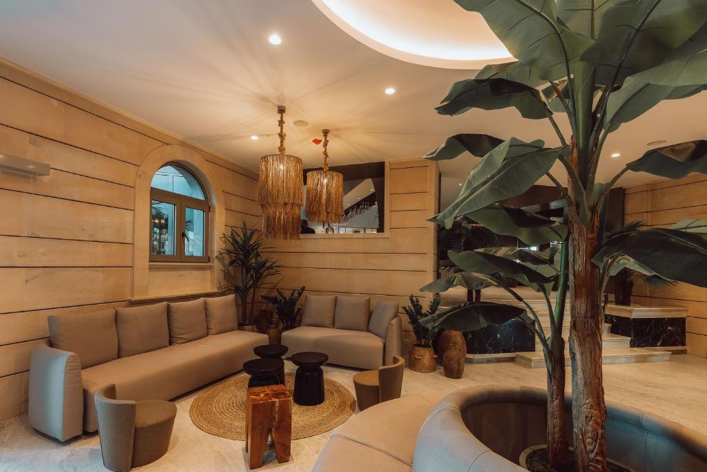 Mūsdienīgs viesistabas interjers ar pelēku dīvānu, augu rotājumiem un stilīgām lampām. Telpa ir eleganti iekārtota ar dabīgiem materiāliem un patīkamu apgaismojumu.