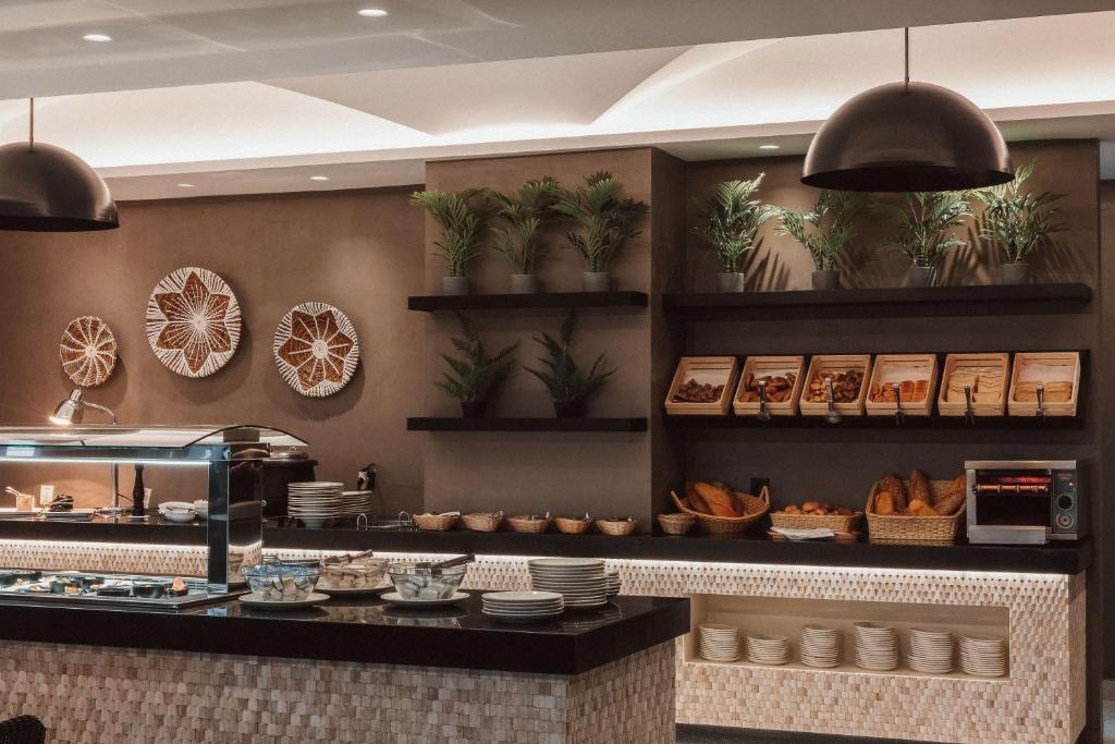Moderns restorāns ar elegantu bufeti, dekorēts ar augu elementiem un mākslinieciskām sienas rotām, piedāvā plašu ēdienu klāstu un siltu maizi.