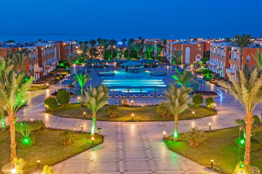 Skats uz baseinu un dārzu pie Sunrise Garden Beach Resort naktī.