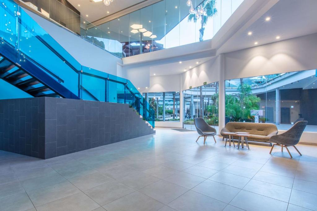 Mūsdienīgs interjers ar stikla kāpnēm un atvērtu telpu, kurā ir dabiska apgaismojuma un augu elementu klātbūtne. Komfortablas mēbeles veido patīkamu atpūtas zonu.