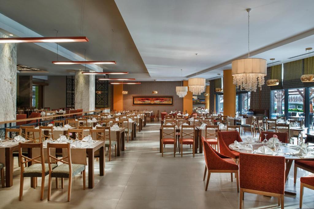 Restorāns Aska Lara Resort & Spa ar eleganti klātiem galdiem.