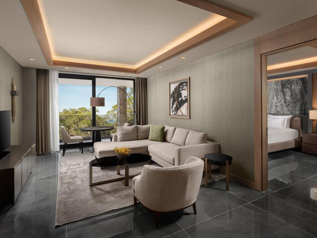 Mūsdienīgs viesnīcas numurs hotelā NG Phaselis Bay ar ērtu dīvānu un skatu uz dabu.