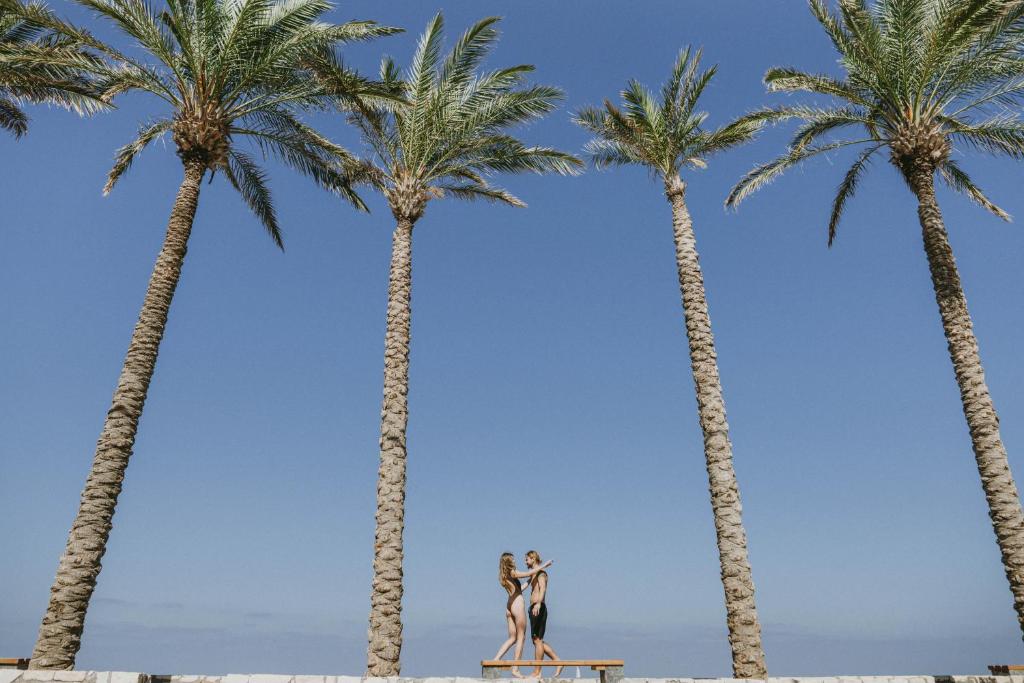 Pāris priecīgi dejo pie palmu rindas pie Infinity Blue Boutique.