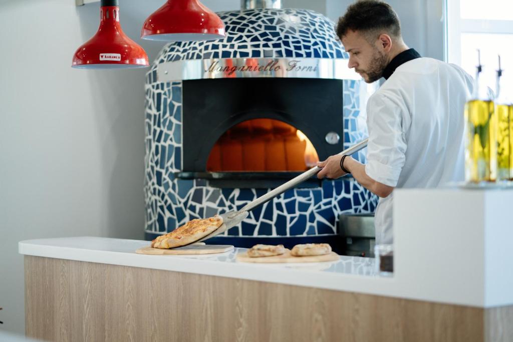 Pavārs, kas izņem picas no akmens krāsns Infinity Blue Boutique
