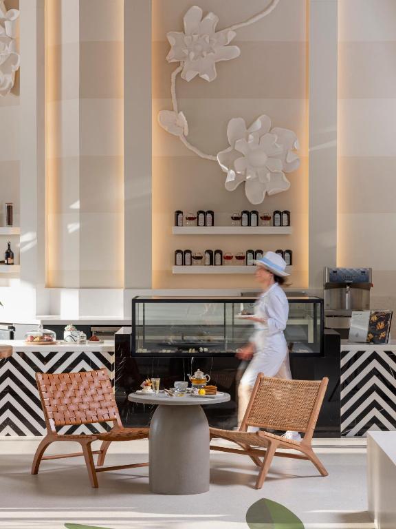 Rixos Premium Bodrum kafejnīca ar modernu interjeru un apkalpojošiem darbiniekiem.