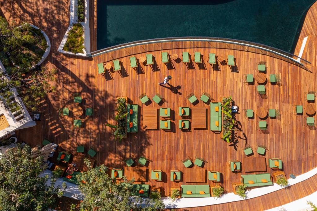 Pārskats uz atpūtas zonu pie baseina Rixos Premium Bodrum ar zaļām krēslu grupām.