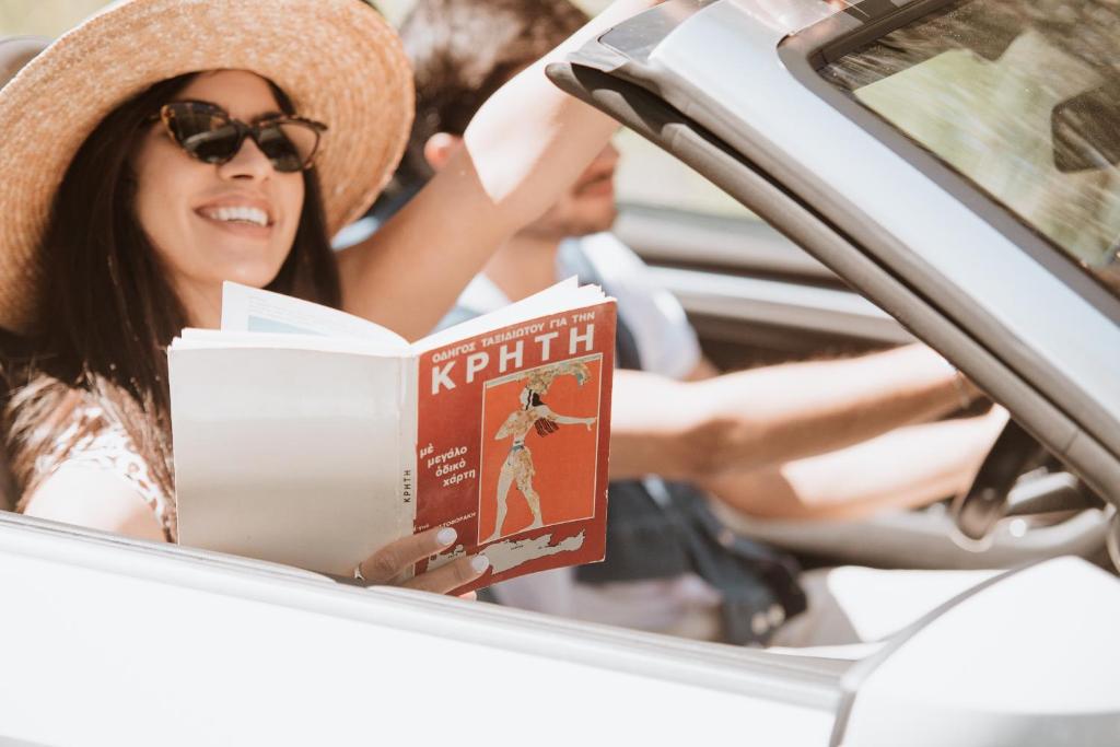 Jauna pāra ceļojums ar auto, lasot grāmatu par Kreta, piekrastē.