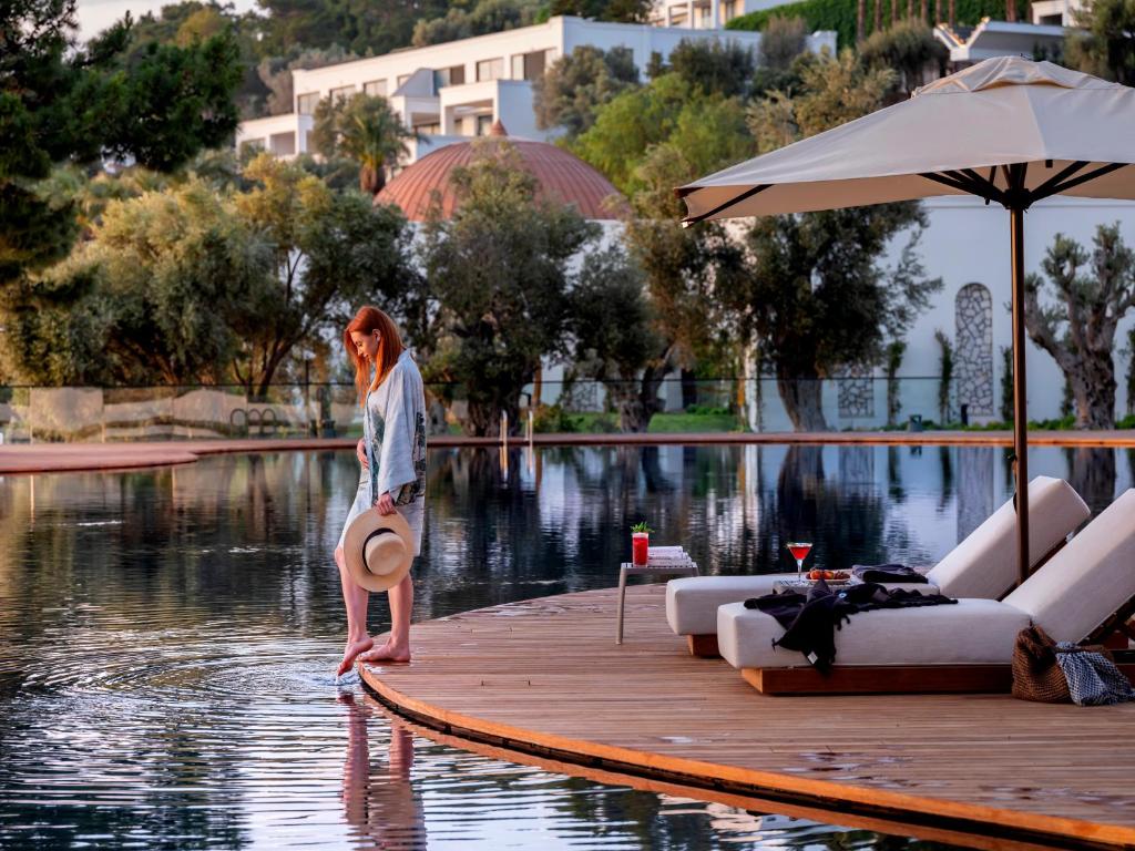 Sieviete stāv pie ūdens pie Rixos Premium Bodrum viesnīcas