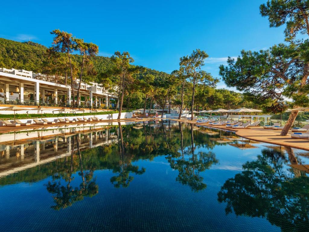Rixos Premium Bodrum viesnīcas baseins ar atspulgu un apkārtējiem kokiem.