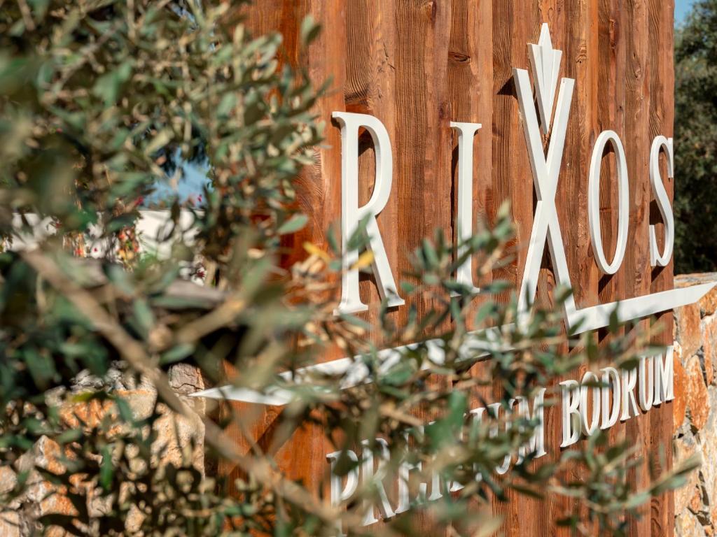 Rixos Premium Bodrum zīme piekrastē starp olīvkokiem.