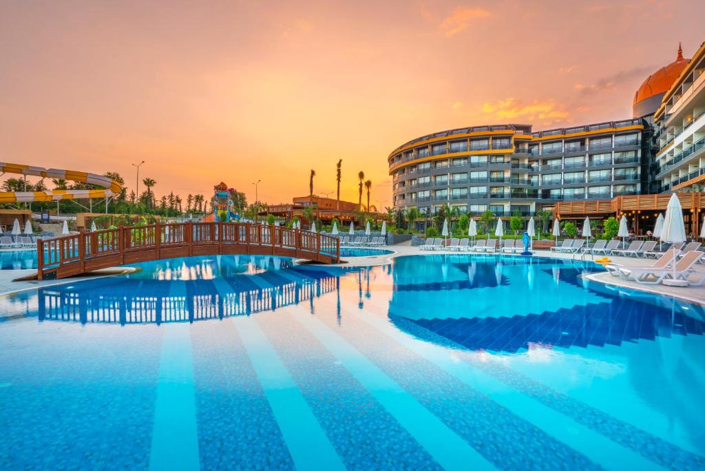 Ainava pie Arnor De Luxe Hotel & Spa ar baseinu un tiltu saulrietā.