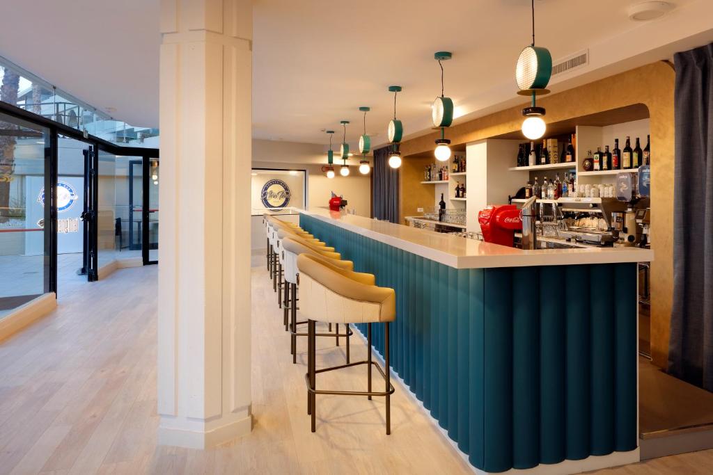 Mūsdienīga bāra interjers ar garu, gaišu letīti un stilīgām lampām. Bāra aizmugurē redzami plaukti ar dzērieniem un kafijas aparāts.