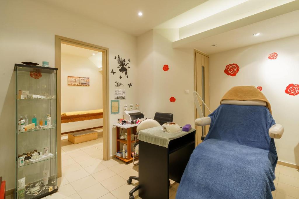 Skaistumkopšanas salons ar relaksējošu atmosfēru, kurā redzams masāžas galds, estētikas aprīkojums un dekoratīvi elementi ar ziediem uz sienām.