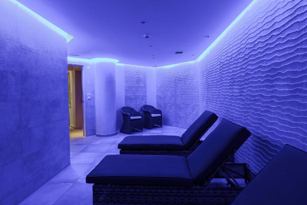 Mūsdienīgs spa telpas interjers ar relaksējošu zilo apgaismojumu un komfortablām atpūtas krēslu grupām.