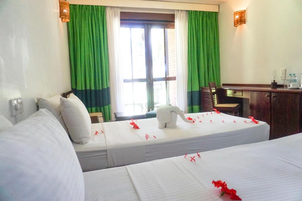 Viesnīcas Club Bentota numurs ar zaļiem aizkariem un ziedu dekorācijām.