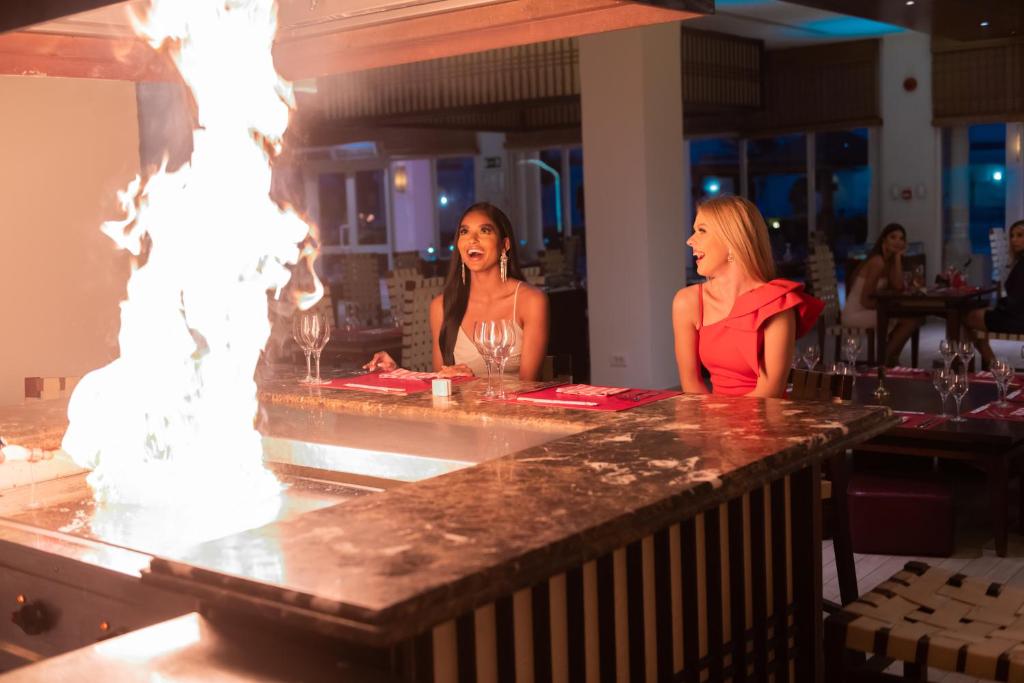 Divas viesnīcas Sunrise Grand Select Montemare Resort viesnīcas viesmīlīgas sievietes sēž pie galda, baudot ēdināšanu ar uguni.