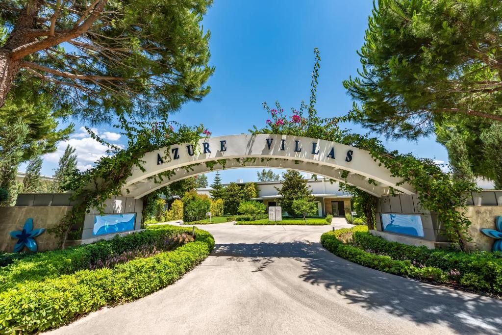 Ieeja uz Azure Villas viesnīcu ar zaļām ainavām un ziediem.