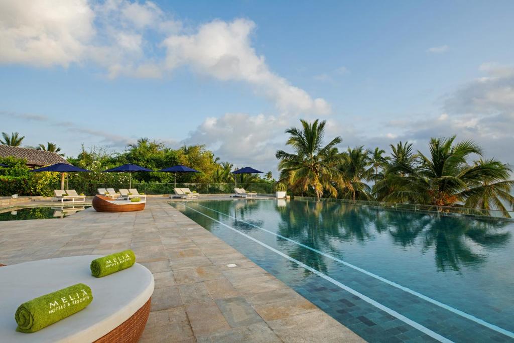 Melia Zanzibar baseins piekrastē ar palmām un saulessargiem