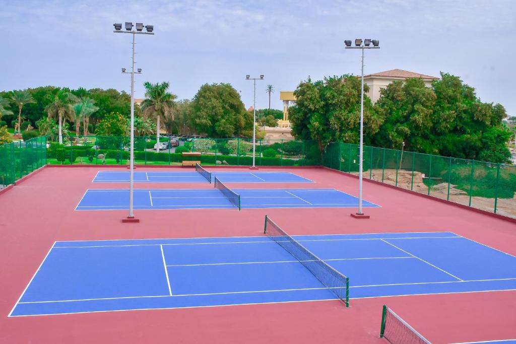 Tenisa korti ar zilu segumu un apgaismojumu, apkārt zaļojošām palmām un augiem. Ideāla vieta sportam un atpūtai.