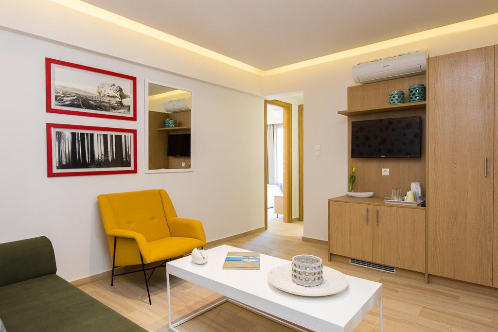 Mūsdienīgs viesistabas interjers ar dzeltenu krēslu, baltu galds un televizoru. Sienas rotā mākslinieciski izstrādātas gleznas un spogulis.