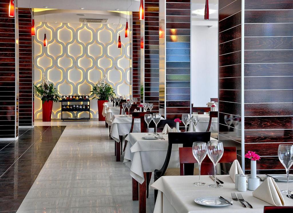 Mūsdienīgs restorāns ar elegantām galdiem un izsmalcinātu interjeru, kas ietver dekoratīvas gaismas un zaļumus. Šī vide ir ideāla romantiskām vakariņām vai svinībām.