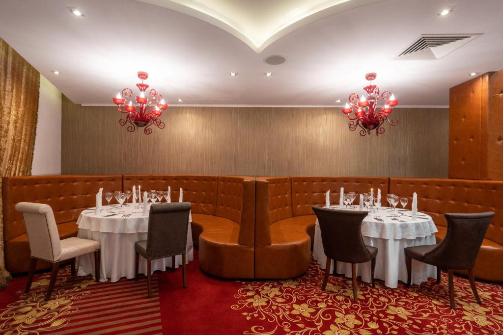 Elegants restorāna interjers ar apaļām galdiem, kā arī ērtiem krēsliem un izsmalcinātu sarkanu lustru. Sienas dekorētas ar zeltainiem aizkariem un tekstūru.