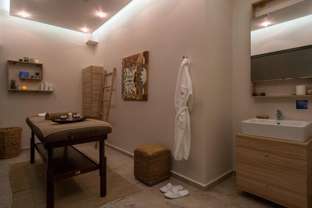 Mājīgs spa telpa ar masāžas galdu, koka plauktiem un relaksējošu apgaismojumu. Telpā ir pieejami masāžas eļļas un dvieļi, radot mierīgu atmosfēru atpūtai.