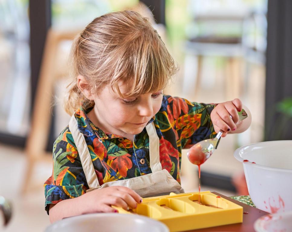 Bērns gatavo desertus viesnīcā LUX Grand Baie, izmantojot krāsainu veidni.