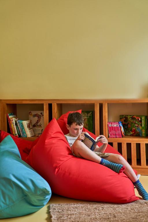 Bērns lasa grāmatu uz spilveniem viesnīcā LUX* Grand Baie