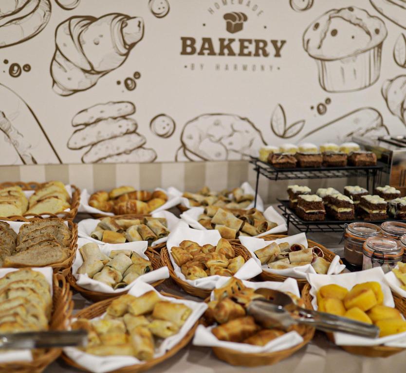 Svaigu maizes un konditorejas izstrādājumu izlase, kas izkārtota grozos un uz plauktiem, fons ar zīmējumiem par maiznīcu.