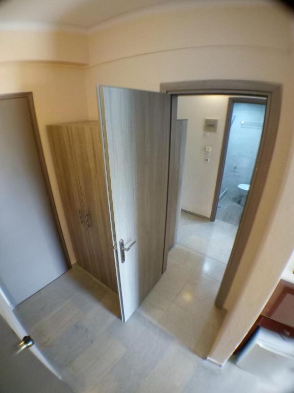 Telpas skats ar atvērtām durvīm, kas ved uz vannas istabu un skapīti. Gaišas sienas un grīdas flīzes rada modernu un tīru atmosfēru.