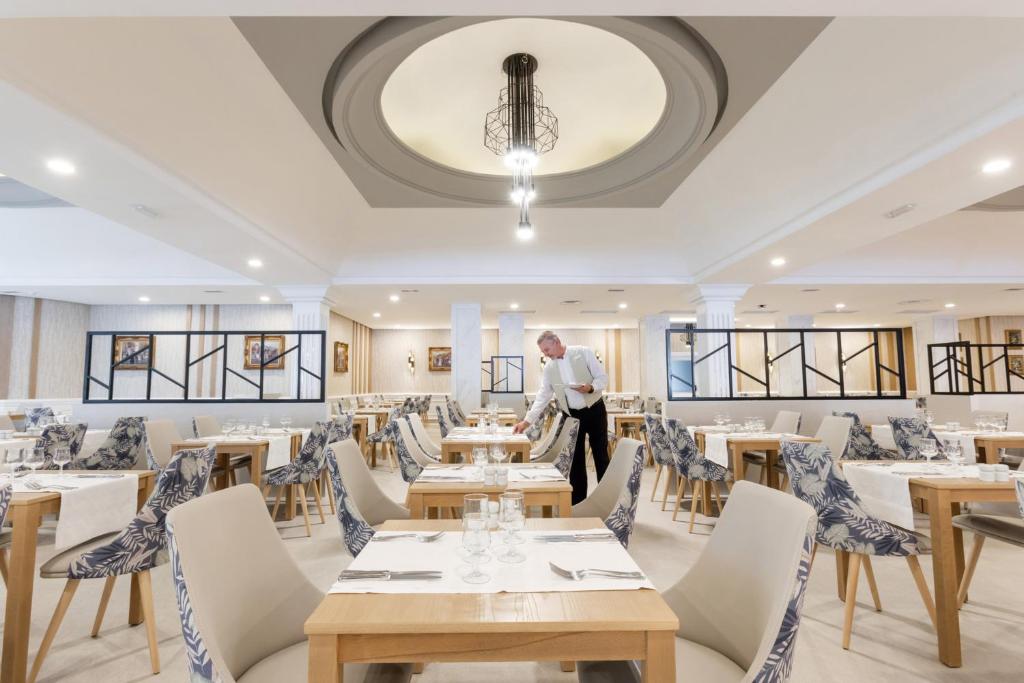 Restorāns ar elegantiem galdiem un personālu, kas apkalpo viesus, Riu Madeira