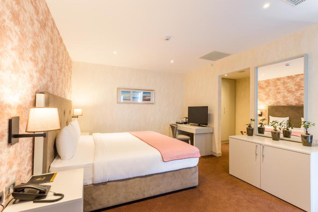 Mūsdienīgs viesnīcas numurs ar ērtu gultu, darba galdu un televizoru, radot patīkamu un relaksējošu atmosfēru. Dekorēts ar siltām krāsām un augiem, kas piešķir mājīgumu.