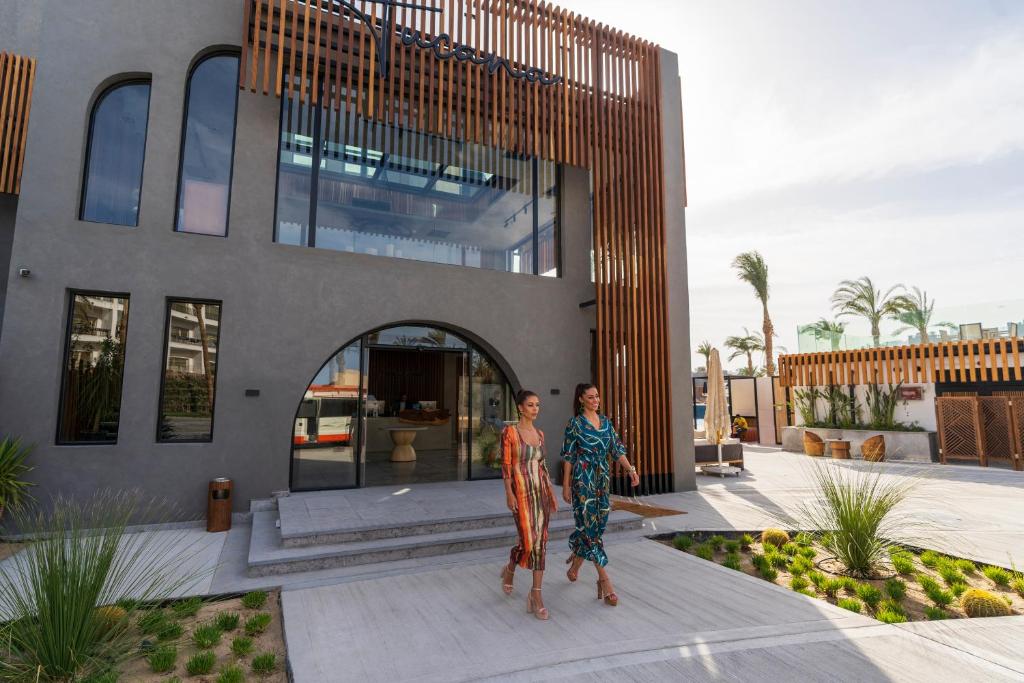 Divas sievietes staigā pie viesnīcas Sunrise Tucana Resort, moderna fasāde.