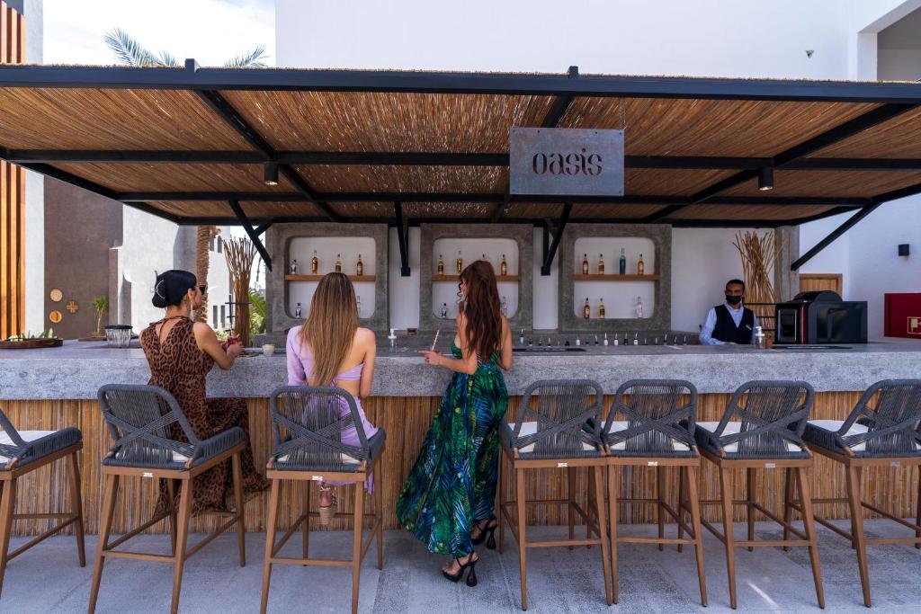 Trīs viesi pie Oasis bāra Sunrise Tucana Resort, baudot dzērienus.