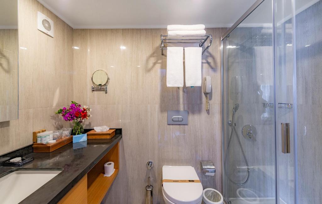 Mūsdienīga vannas istaba Samara Hotel Bodrum ar dušu un ziediem.