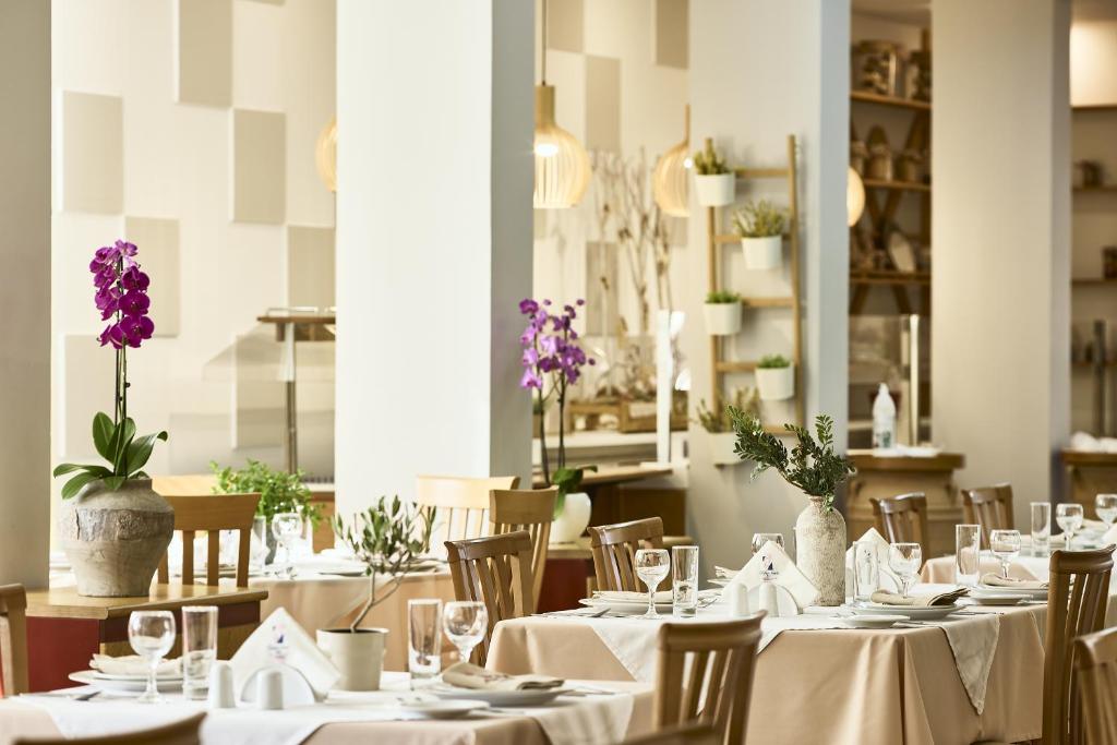 Grezns restorāna iekārtojums ar ziediem uz galdiem un mūsdienīgu interjeru, kas rada mājīgu atmosfēru.