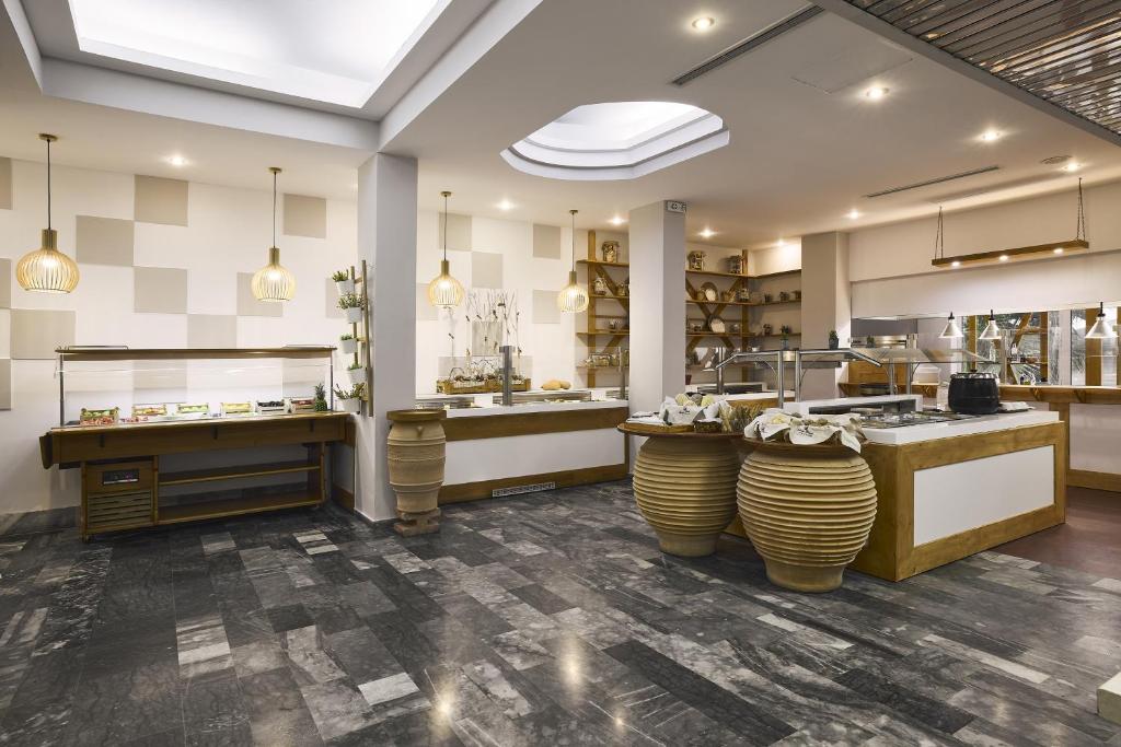 Mūsdienīga kafijas veikala interjers ar elegantiem gaismekļiem un stilīgām mēbelēm, kas rada siltu un viesmīlīgu atmosfēru. Interjerā redzami koka akcenti un plaša galdu izvēle, kas paredzēta ēdienu pasniegšanai.