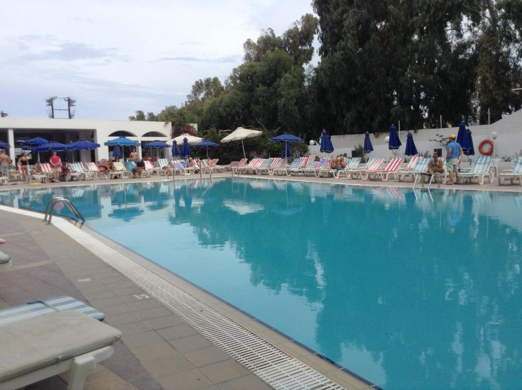 Liels baseins viesnīcā Belair Beach ar sauļošanās krēsliem un saulessargiem.