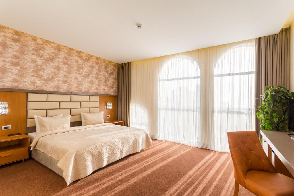 Mūsdienīgs viesnīcas numurs ar plašu gultu un lieliem logiem, caur kuriem ieplūst dabiska gaisma. Interjers ir elegants, ar siltām krāsām un mūsdienīgu mēbelēšanu.