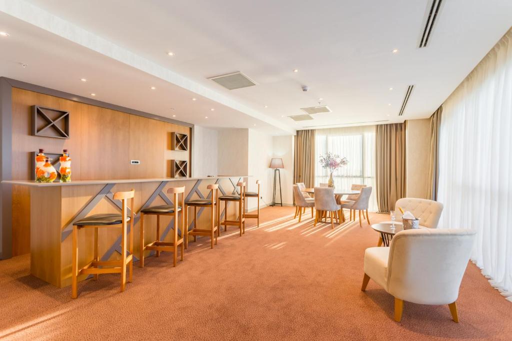 Mūsdienīgs viesnīcas numurs ar koka bāru, ērtām krēslām un dabīgu apgaismojumu. Interjers ir gaišs un elegants, radot relaksējošu atmosfēru.