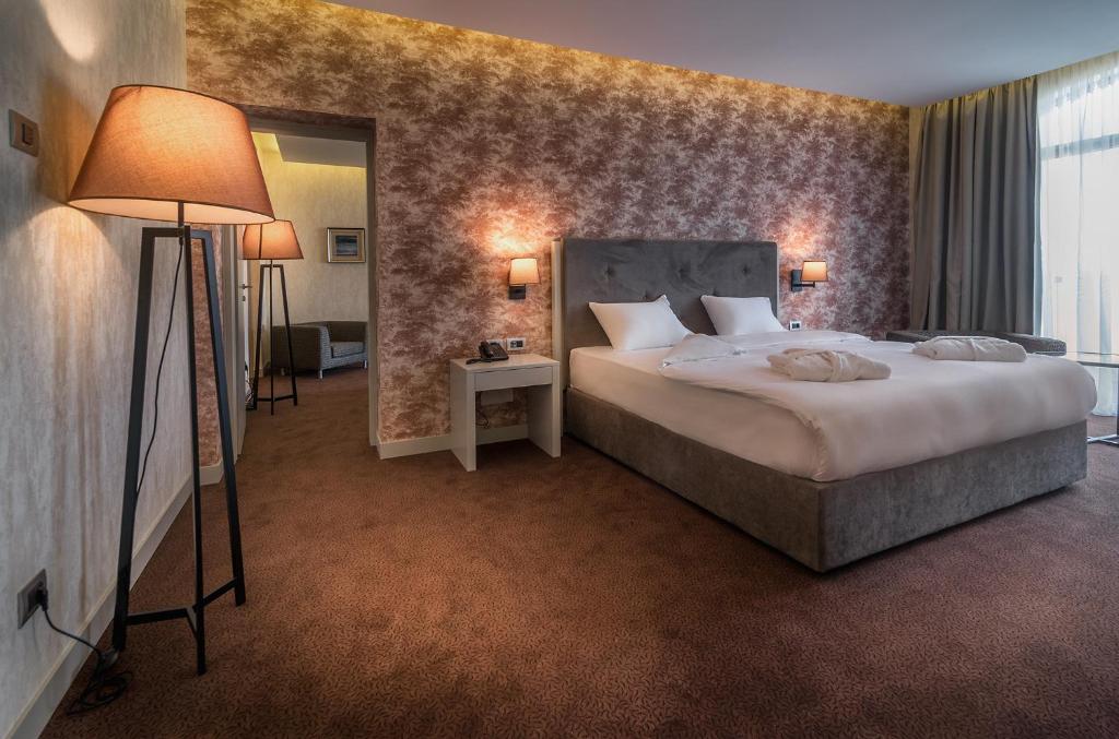 Mūsdienīgs numurs ar divguļamo gultu, stilīgu lampu un siltām krāsām, radot mājīgu atmosfēru. Logi ar aizkariem nodrošina dabisko apgaismojumu.