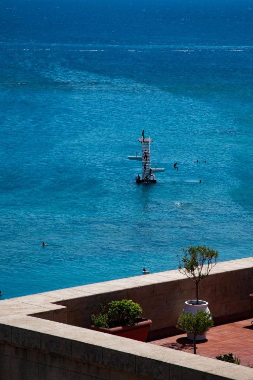 Skats uz jūru no Grande Albergo Delle Rose, cilvēki peld un ir uz dēļa.