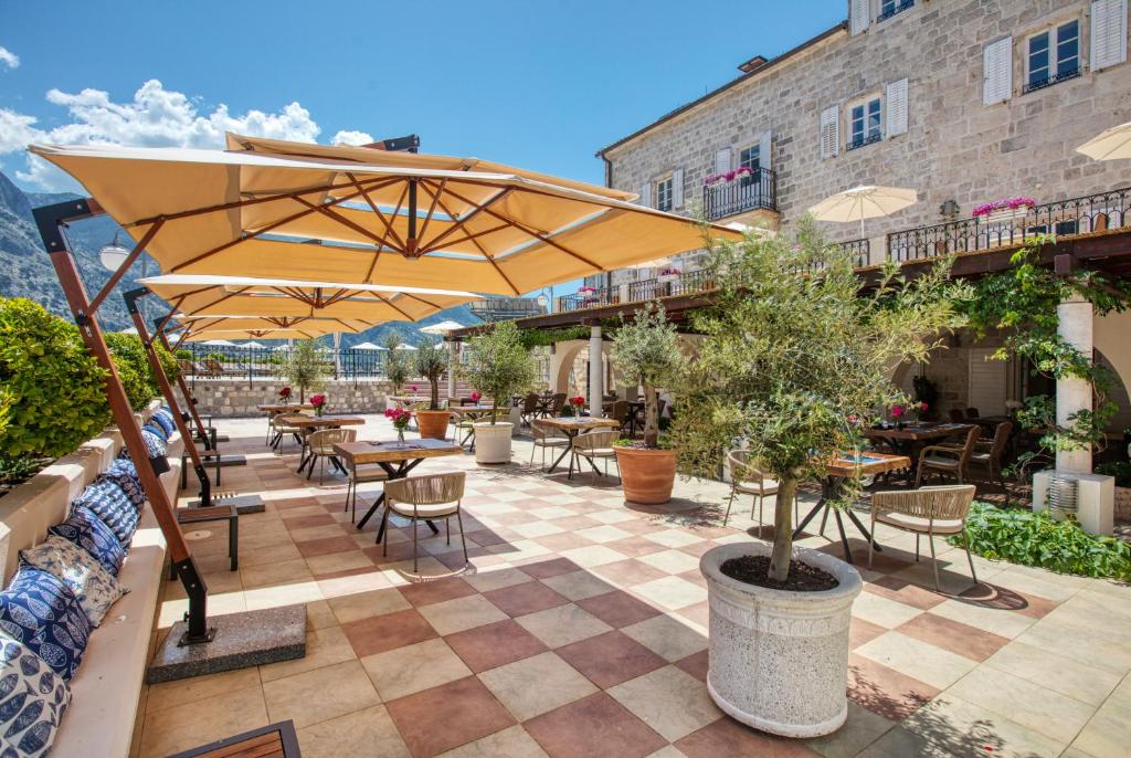 Šis ir mūsdienīgs restorāna āra terases skats ar saulessargiem, koka galdiem un krēsliem, kas ierāmēts ar zaļumiem un kalnu ainavu. Ideāla vieta, lai izbaudītu maltītes svaigā gaisā.