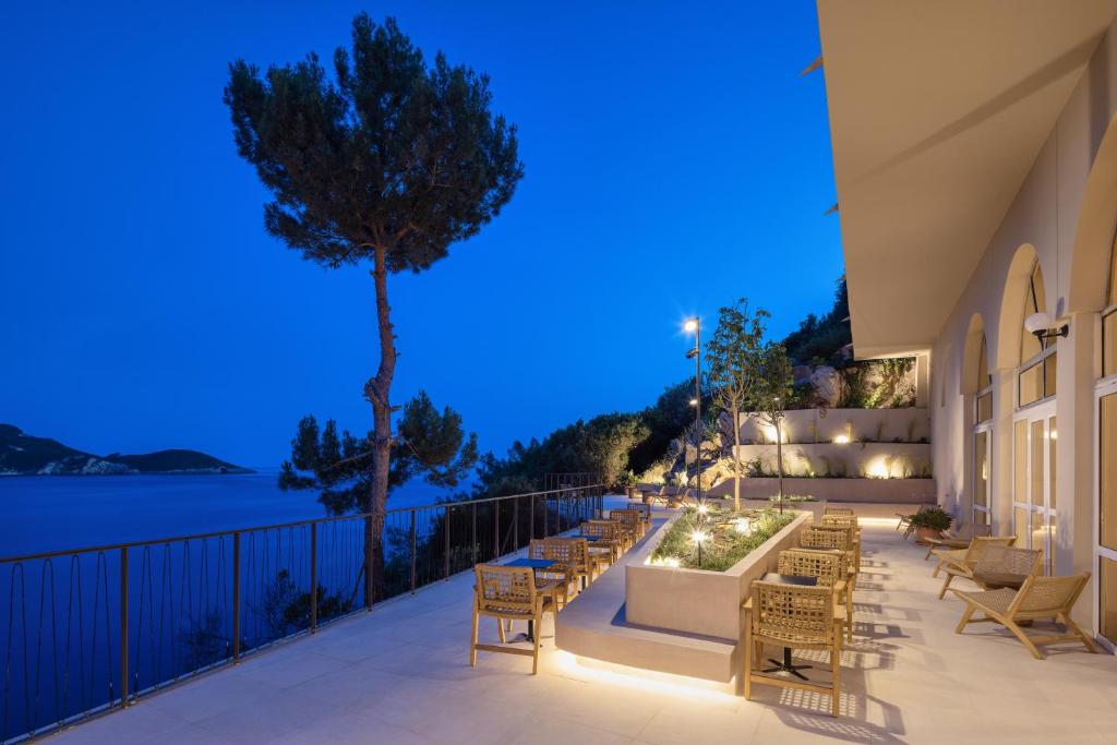 Mūsdienīgs terases skats pie jūras ar komfortablām mēbelēm un apgaismojumu, kas veido relaksējošu atmosfēru. Zilā stunda rada burvīgu noskaņu.