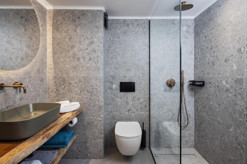 Mūsdienīgs vannas istabas interjers ar akmens apdari, stikla dušu un dekoratīvu izlietni. Eleganti elementi un neitrālas krāsas rada relaksējošu atmosfēru.